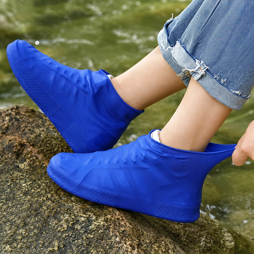 Reusable waterproof silicone rain shoe covers worn outdoors on wet rocks with non-slip grip