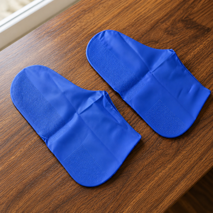 Pair of reusable blue waterproof silicone rain shoe covers on wooden table
